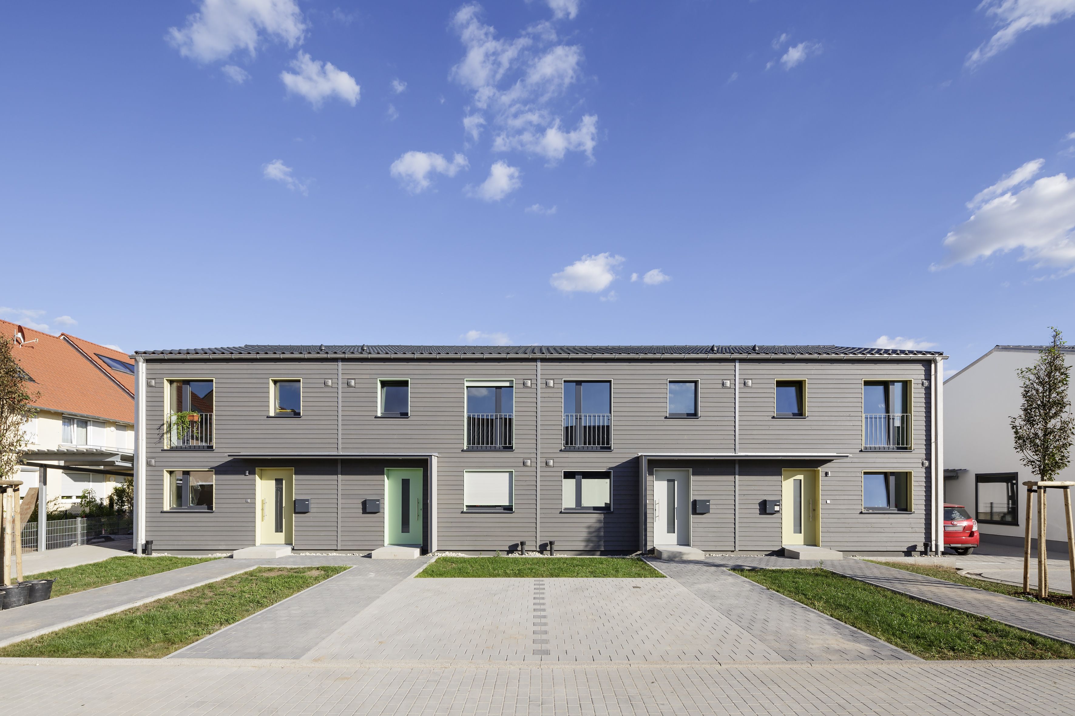 Straßenseite der Reihenhäuser mit Eingänge und Parkplätze